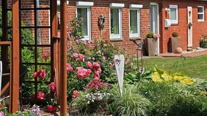 A brick house with a garden, a wooden gate, and a bird sculpture.