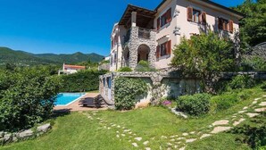 A two-story house with a stone facade, a swimming pool, and a lush garden. - Holiday home with pool, sauna and gym (Opatija)