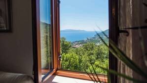 A room with a large window offering a view of a coastal landscape. - Holiday home with pool, sauna and gym (Opatija)
