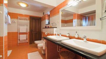 A bathroom with two sinks, a toilet, a towel rack, and a mirror.