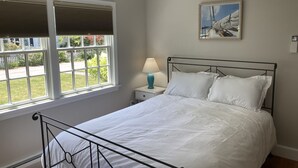 A bedroom with a bed, a nightstand, a lamp, a window with blinds, and a painting on the wall. -  Downtown Edgartown Historic District. Walk to town and harbor. (Edgartown)