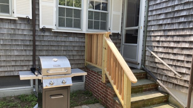 An outdoor grill setup with a chimney, a wooden staircase, and a brick wall. -  Downtown Edgartown Historic District. Walk to town and harbor. (Edgartown)