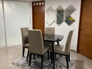 A dining area with a round table and four chairs, a fluffy rug, and a wall-mounted mirror. - Apartamento (Santa Marta)