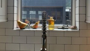 Une cuisine avec une fenêtre donnant sur un immeuble moderne et des montagnes.