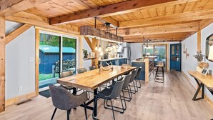 A spacious kitchen with a long wooden table, modern chairs, and a built-in island. - Beautiful chalet on 5 acres - 2 min to Village!👌 Hot-Tub, Sauna, Fire Pit🔥 (Ellicottville)