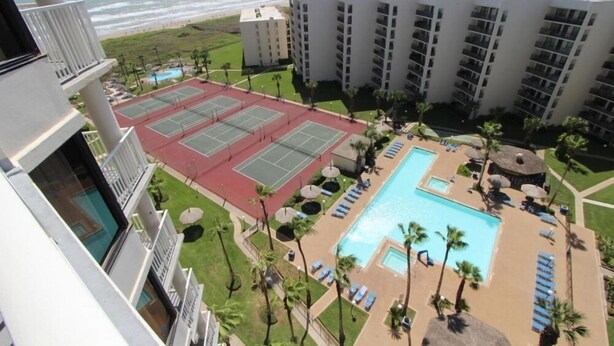 Ein Hotel mit Pool, Tennisplätzen und Meerblick.