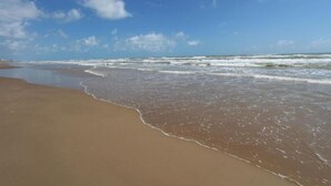 Ein Strand mit sanft anschwellenden Wellen und einem klaren Himmel.