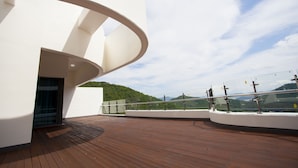 Een modern gebouw met een gebogen witte gevel en een houten terras.