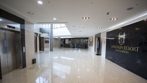 Een ruime lobby met een gepolijste marmeren vloer, een receptiebalie en een lift.