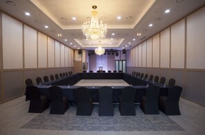 A conference room with a long table, chairs, a chandelier, and a stage with a podium. - Dongwon Royal Country Club & Resort (Tongyeong)