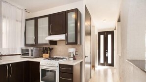 A modern kitchen with dark cabinets, a microwave, a stove, and a coffee maker. - Villa Centro Casa Divina (Oaxaca)