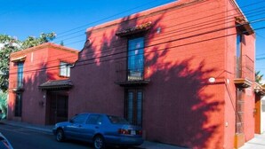 A red building with a parked car in front. - Villa Centro Casa Divina (Oaxaca)