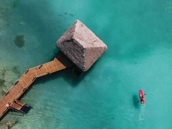 An overwater bungalow with a wooden deck and a thatched roof. - Khaban Bacalar Hotel Boutique (Bacalar)