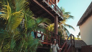 A wooden staircase leading to a thatched-roof structure surrounded by lush palm trees. - Khaban Bacalar Hotel Boutique (Bacalar)