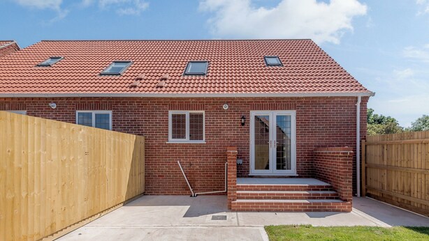 A two-story brick house with a red-tiled roof, a front door with glass panels, and a small front porch. - Dawson Park 5 - UK12664 (Mablethorpe)
