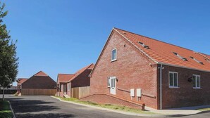 A residential street with brick houses, a clear sky, and a paved road. - Dawson Park 5 - UK12664 (Mablethorpe)