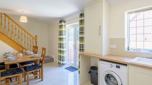 A clean, modern kitchen with a built-in washing machine, wooden dining table, and chairs. - Dawson Park 5 - UK12664 (Mablethorpe)