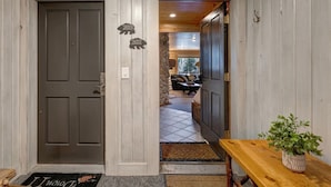 A wooden interior hallway with a closed door labeled '203' and '202', a bench, and a potted plant.