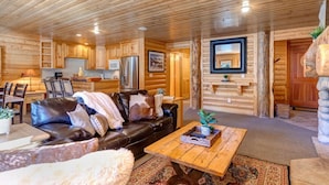 A log cabin interior with a living room, dining area, and kitchen.