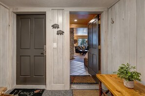 A hallway with a wooden door, a welcome mat, and a bench with a potted plant.
