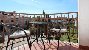 Ein Balkon mit zwei Korbstühlen und einem kleinen Tisch, umgeben von einem Holzzaun.