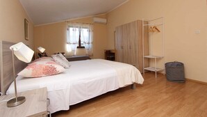 Een slaapkamer met een bed, bedlampen, een kledingkast, een droogrek en een prullenbak.