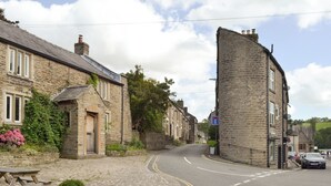 Un edificio de piedra con un camino de entrada curvo y una mesa de picnic al lado.