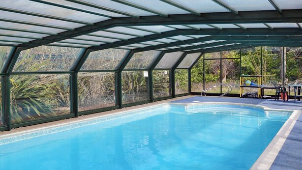 Una piscina interna con soffitto in vetro, immersa nel verde.