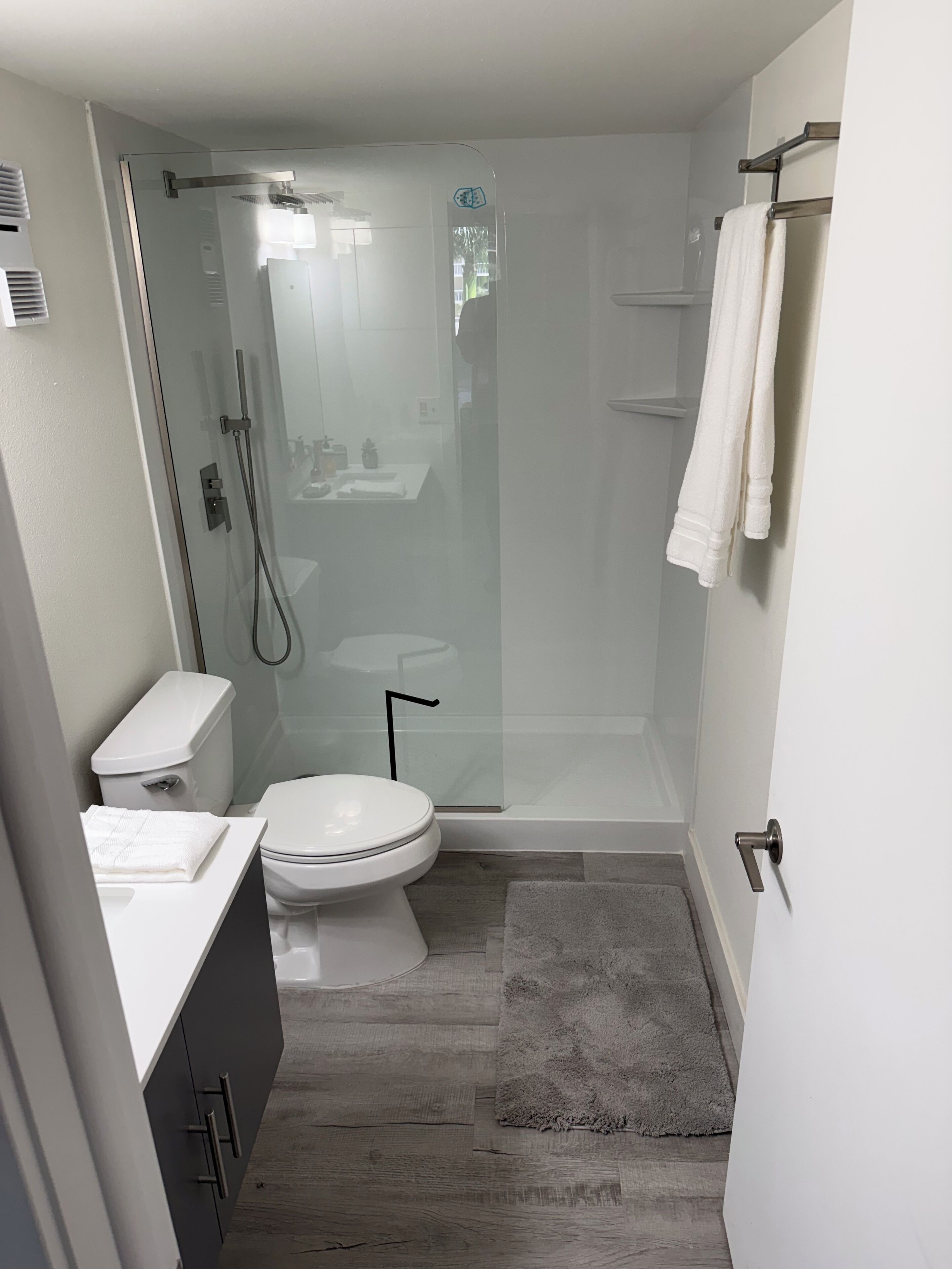 Un baño compacto con ducha de vidrio, inodoro y lavamanos.