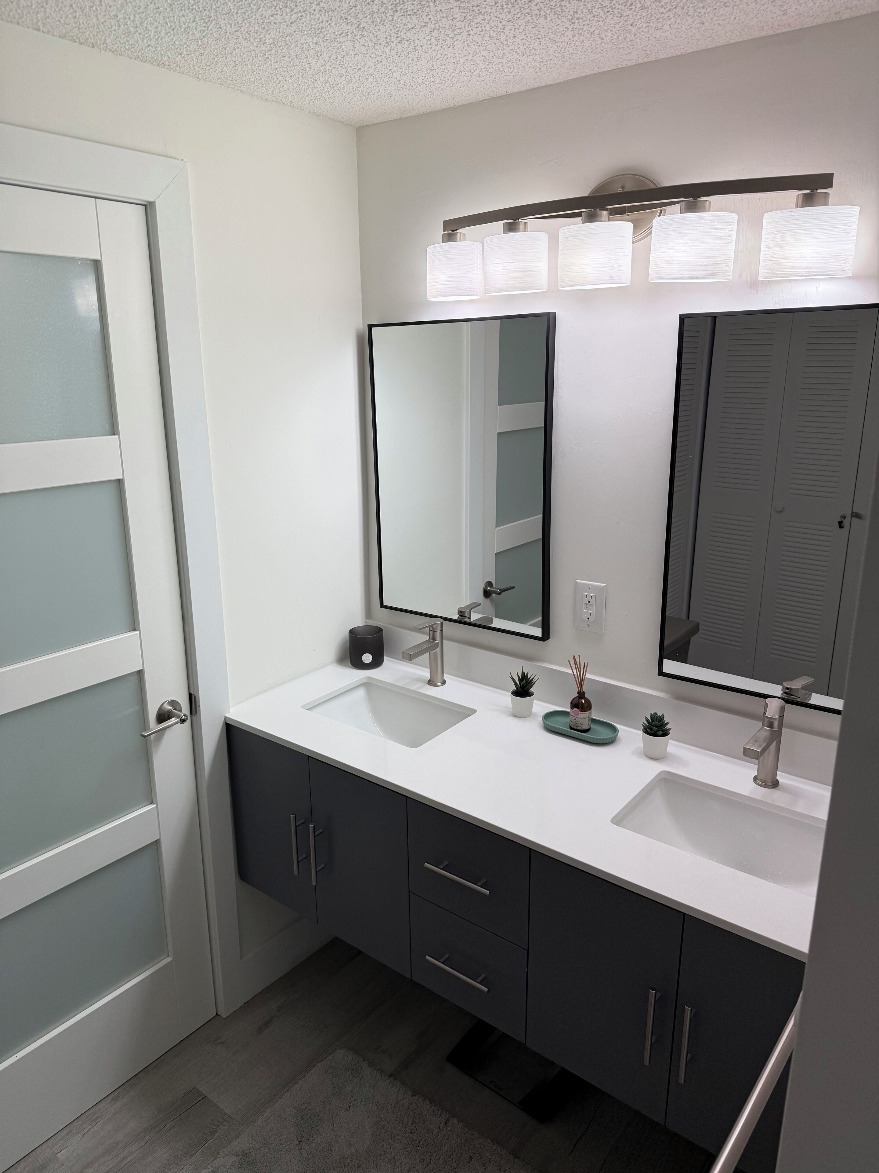 A modern bathroom with two sinks, a large mirror, and a cabinet with drawers.