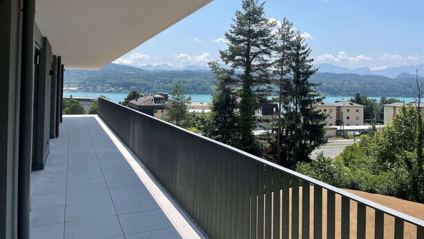 En balkon med udsigt over et sølandskab, bjerge og bygninger.