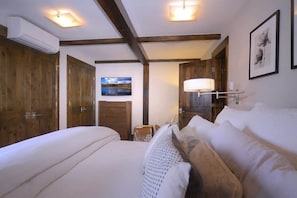 A bedroom with a bed, wooden wardrobe, a TV, and a lamp.