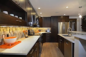 A modern kitchen with dark cabinetry, stainless steel appliances, and a white countertop.