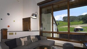 Un salon moderne avec une grande fenêtre, un canapé, une table basse ronde et une lampe.