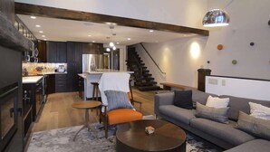 Un salon moderne avec un canapé, une table basse et un escalier menant à un espace cuisine.
