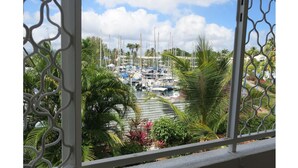 A marina with numerous boats docked, surrounded by lush greenery and palm trees. - Studio Terrace sea view (Les Trois-Îlets)