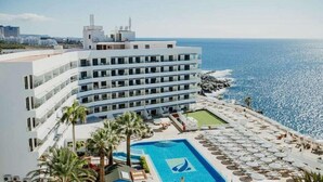 A hotel with a pool area, including a large pool and a smaller pool, surrounded by lounge chairs and umbrellas. - Perla Gris Aparthotel (Adeje)