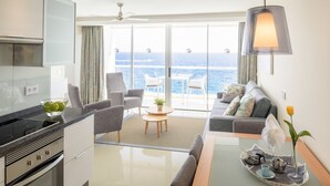 A modern kitchen with a built-in oven and a dining area with a table set for two. - Perla Gris Aparthotel (Adeje)