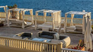 A seaside terrace with outdoor seating, including lounge chairs and a sofa, overlooking the ocean. - Perla Gris Aparthotel (Adeje)
