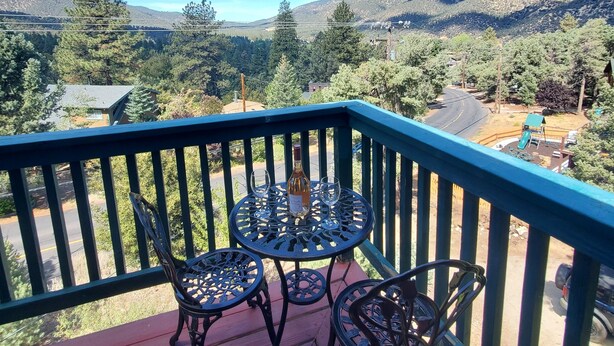 A balcony with a table and chairs, overlooking a mountainous landscape. - Woodland Pines Cabin (Frazier Park)