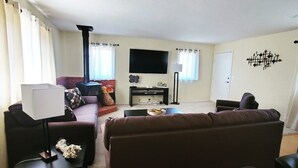 A living room with a sofa, a coffee table, a TV, and a fireplace. - Woodland Pines Cabin (Frazier Park)