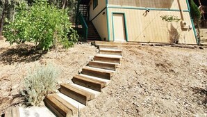 A wooden cabin with a balcony, a staircase leading to the entrance, and a natural surrounding. - Woodland Pines Cabin (Frazier Park)