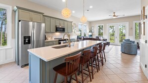 A spacious kitchen with a large island, stainless steel appliances, and pendant lighting.