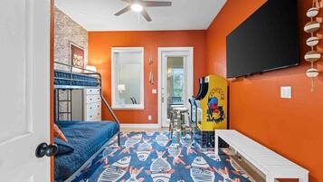 A room with a bunk bed, a ceiling fan, a TV, and a colorful fish-patterned rug.