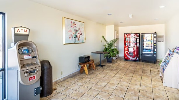 An indoor area with an ATM, vending machines, a small table with a microwave, and a potted plant. - OYO Hotel Oklahoma City Northeast (Oklahoma City)