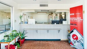 A hotel reception area with a counter, plants, and a red OYO Hotels promotional banner. - OYO Hotel Oklahoma City Northeast (Oklahoma City)