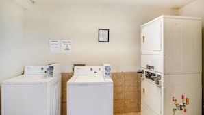 A laundry room with two front-loading washers, a stacked dryer, and a refrigerator. - OYO Hotel Oklahoma City Northeast (Oklahoma City)