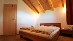 Une chambre à coucher avec un lit en bois, une table de chevet, une lampe fixée au mur et une porte.