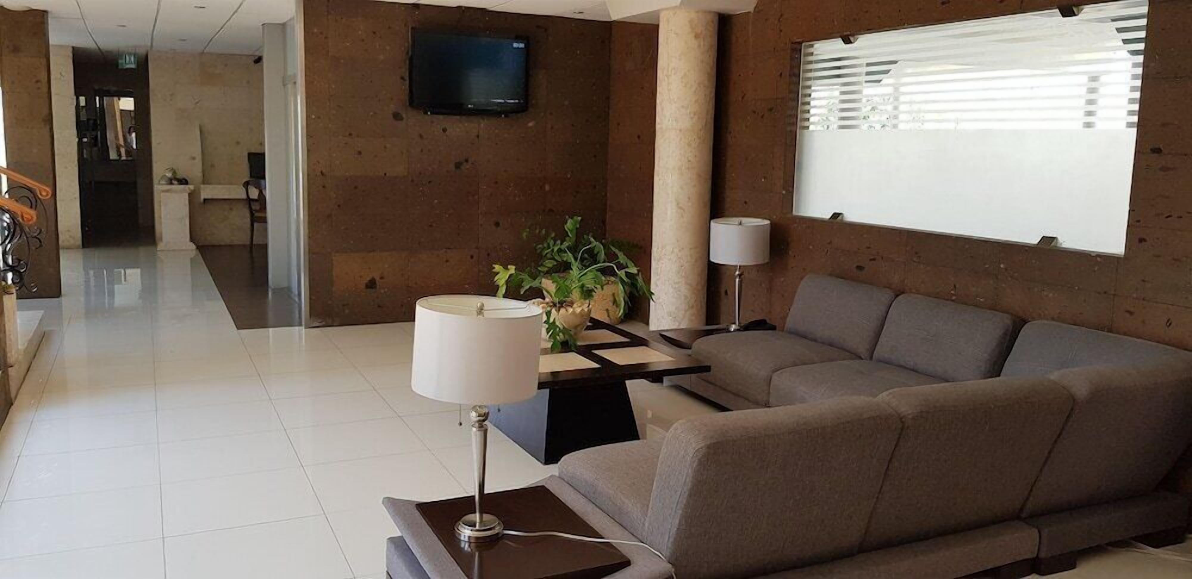A modern living room with a sofa, a coffee table, a lamp, and a television mounted on the wall.