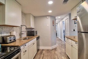 A kitchen with white cabinets, a stainless steel refrigerator, a microwave, and a toaster.